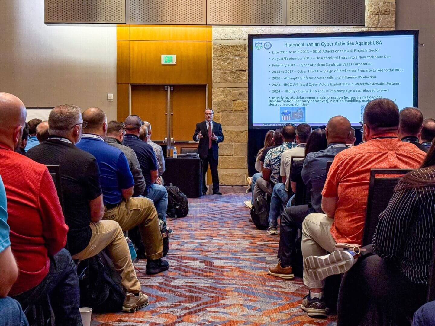 Audience attentively listens to a speaker presenting at a conference.
