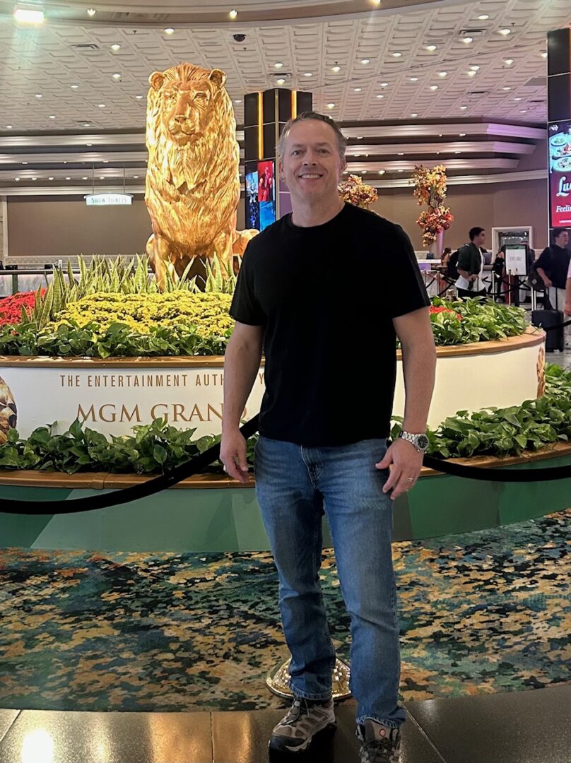 Man standing inside a casino with golden lion statue in background.
