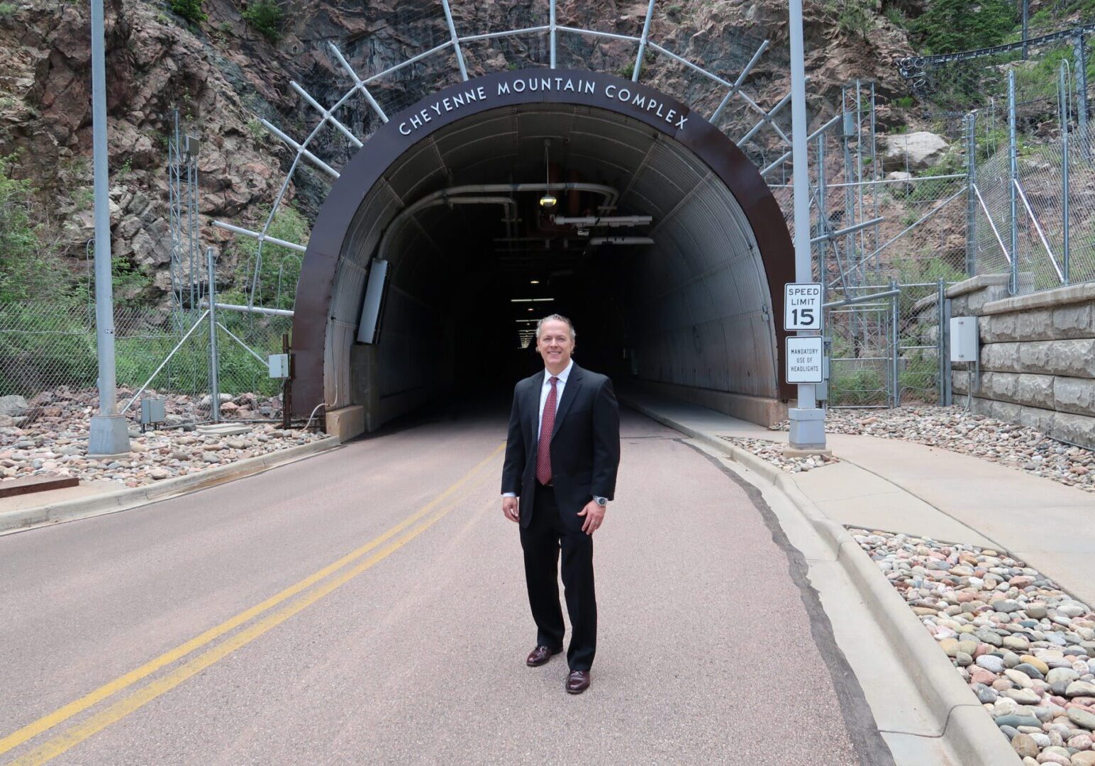 Businessman in front of mountain tunnel entrance.